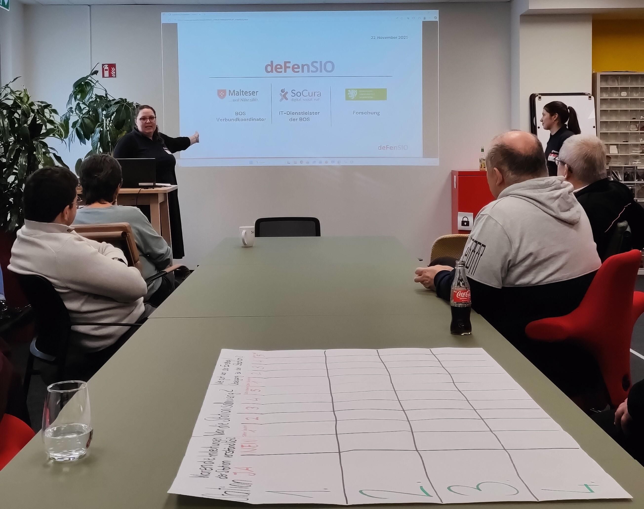 Merle Medick stellt in einem der Escape Rooms die Inhalte des Projekts deFenSIO dar. Ihr hören die Teilnehmenden des Escape Rooms zu.