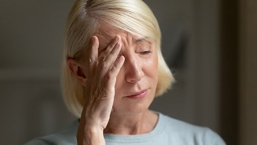 Eine verzweifelte Frau hält sich die Hand vors Gesicht. 