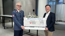 Peter Weiler, Stadtbeauftragter der Malteser in Wiesbaden und Sebastian Albus, Abteilungsleiter Sponsoring & Events bei der Wiesbadener Volksbank halten den Spendenscheck über 5000 Euro.