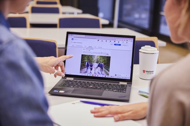 Zwei Personen schauen auf einen Laptop