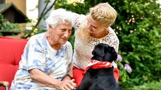 Begleiterin des sozialen Dienstes besucht Bewohnerin mit einem Hund 