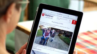 Eine ältere Dame schaut auf ein Tablet