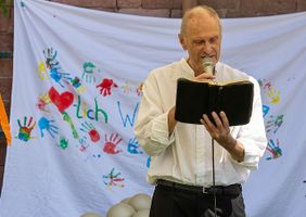 Stephan Skroch stehend auf einer Wiese mit Buch (Foto: Malteser Mainz)