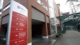 Eingang des Malteser Waldkrankenhaus St. Marien mit rotem Wegweiser und überdachtem Zugang.