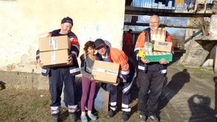 Kinder mit Paketen vor einem gelben Haus