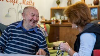 Ein älterer Mann unterhält sich lachend im Café Malta.