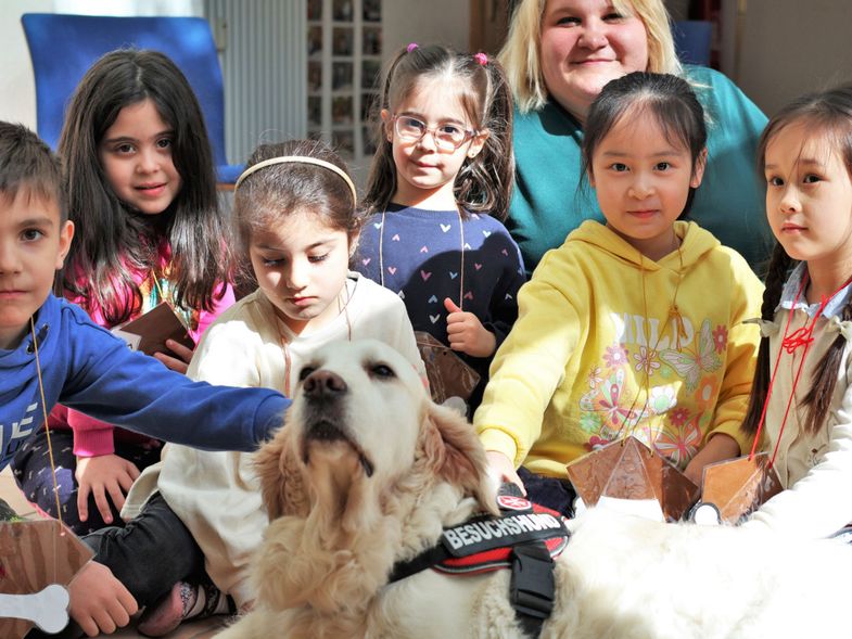 Eine Gruppe Kinder sitzen um einen Hund herum