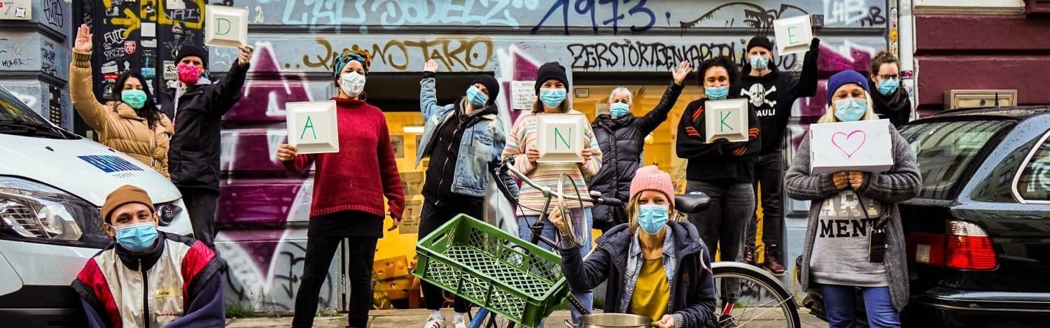 Junge Menschen mit Maske halten Danke-Schilder hoch.