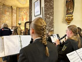 Personen mit Musikintrumenten und Noten.