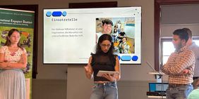 Eine junge Frau erklärt Studierenden etwas