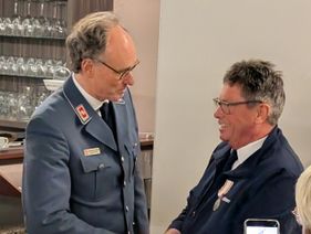 Johannes von der Haar trägt den Verdienstorden an seiner Jacke und Dr. van Lengerich gratuliert