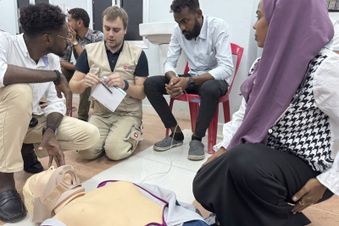 Eine Gruppe Menschen sitzt um eine Puppe. Foto: Malteser International