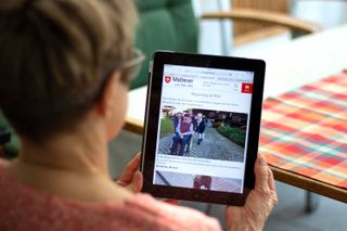 Frau schaut sich das Online-Magazin "dabei" auf einem Tablet an.