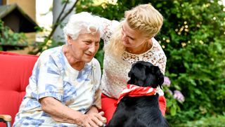 Begleiterin des sozialen Dienstes besucht Bewohnerin mit einem Hund 