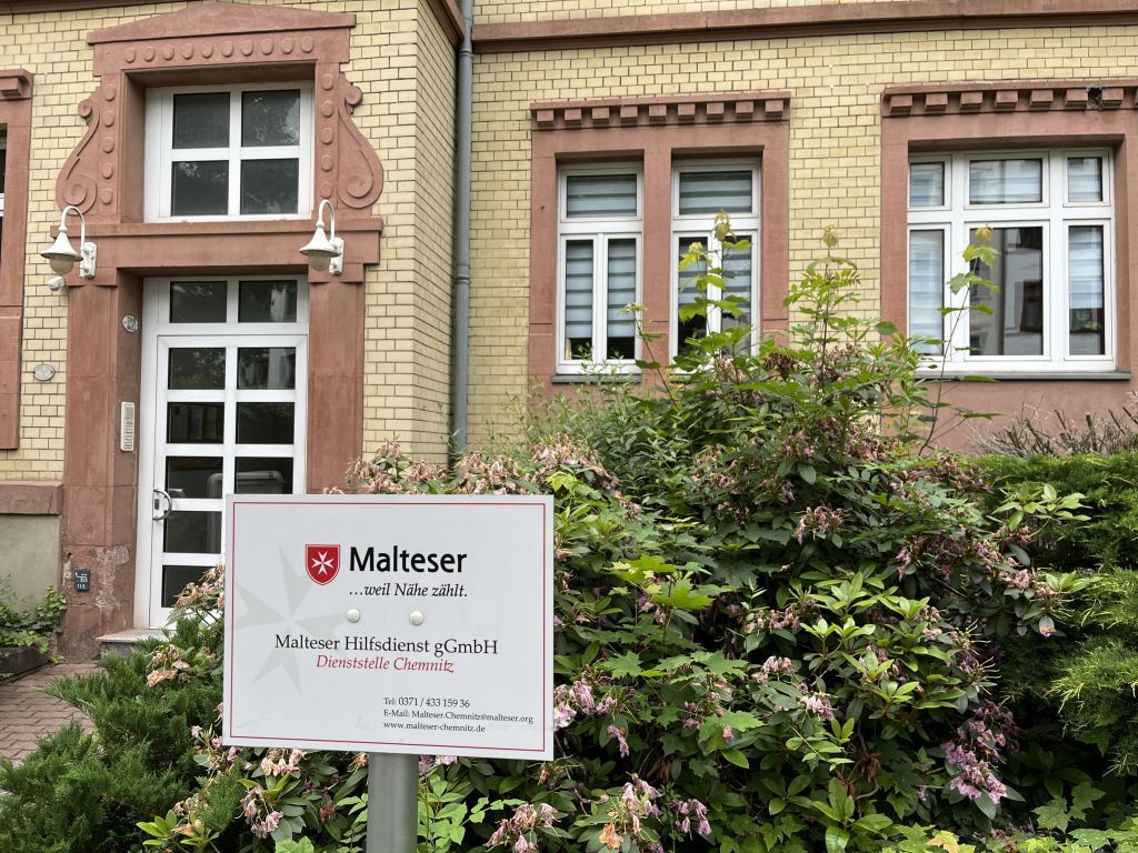 Fassade eines Hauses mit Diensstellenschild davor