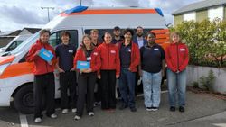 Eine Gruppe Jugendlicher steht vor einem Rettungswagen und lacht