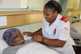 Nurse Nomusa Nxumalo caring for a patient at her bedside.