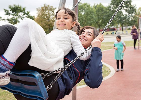 Eine junge Frau schaukelt mit einem Mädchen auf dem Schoß