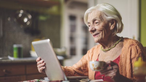 Es ist eine alte Dame zu sehen, welche ihr Tablet nutzt.