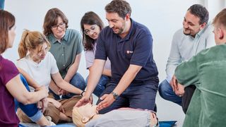 Ausbilder der Malteser Ersten-Hilfe-Kurse erklärt Notfallmaßnahmen an einem Dummy.