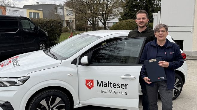 Kreisgeschäftsführer Sebastian Oberpriller und Pflegefachkraft Sabine Grundig stehen vor dem Auto der Malteser Übergangspflege in Freising