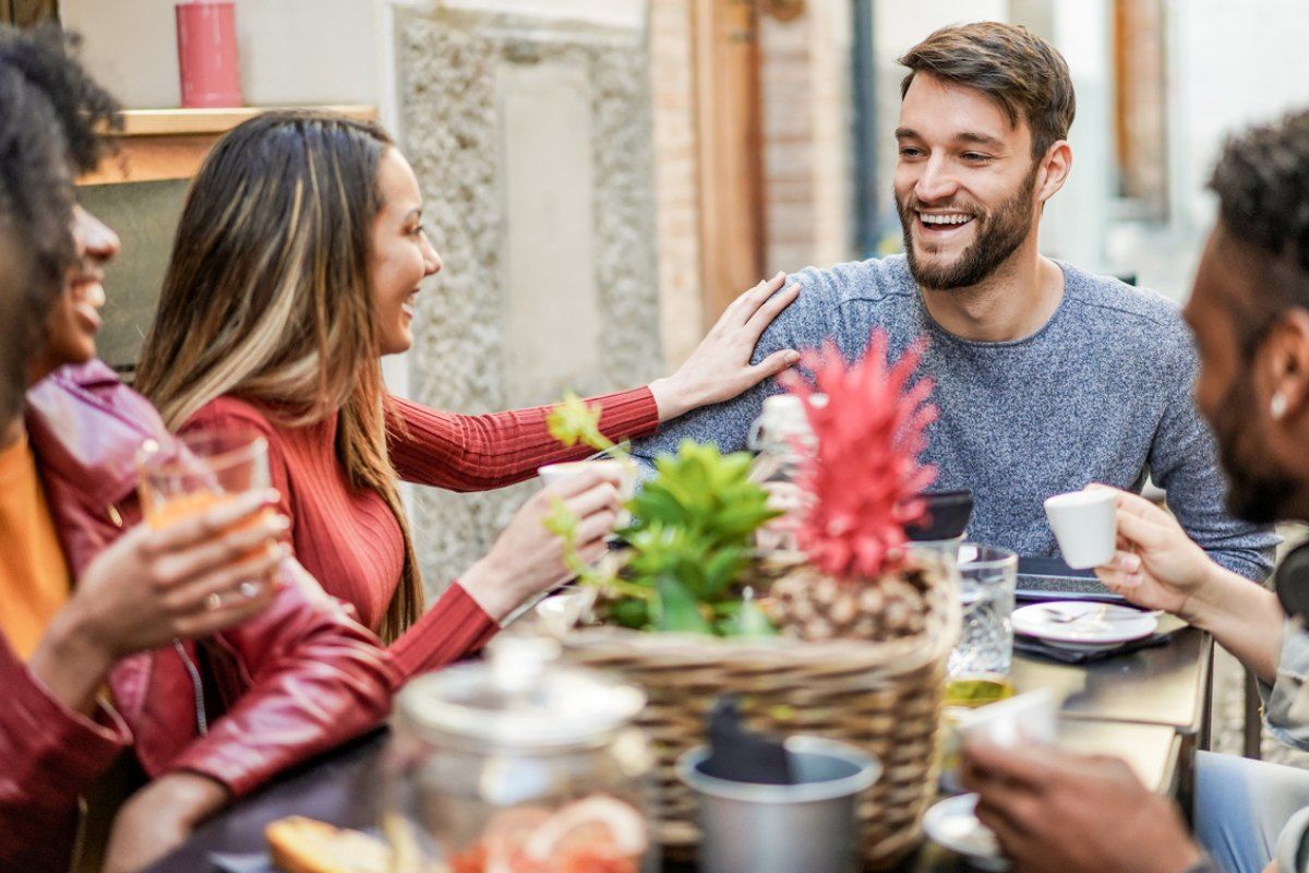 Junge Menschen lachen und essen an einem Tisch