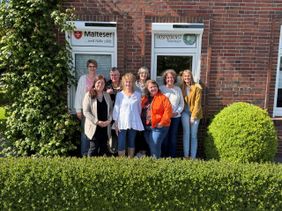 Die Kursteilnehmerinnen und -teilnehmer posieren für ein Gruppenfoto vor den Fenstern des Hospizdienstes der Malteser Twistringen