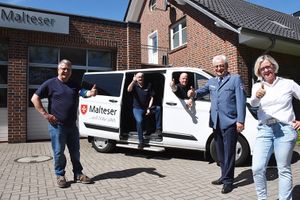 Fünf Personen stehen um einen Malteser Kleinbus und heben die Daumen.