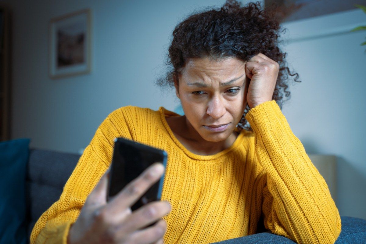 Junge Frau mit besorgtem Gesichtsausdruck schaut auf ein Smartphone