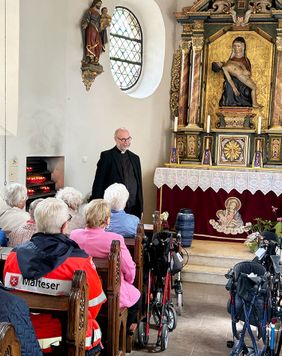 Personen sitzend und stehend, Kapelle, Rollstühle