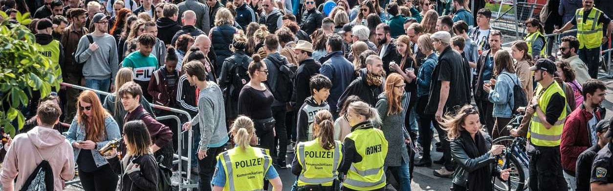 Eine Menschenmenge und Polizistinnen in gelben Warnwesten