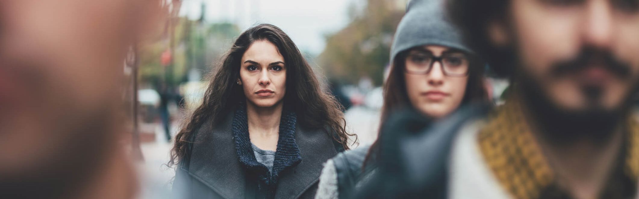 Eine junge Frau sieht unglücklich aus in einer Gruppe junger Menschen