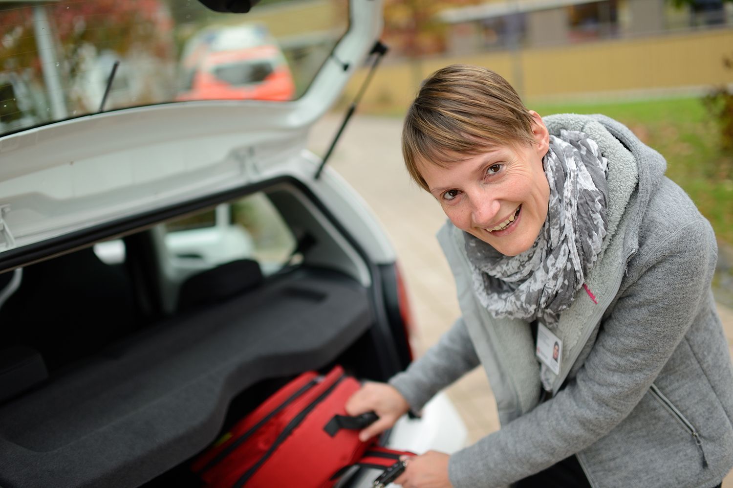 Das Bild zeigt eine Mitarbeiterin eines ambulanten Palliativdienstes am Auto