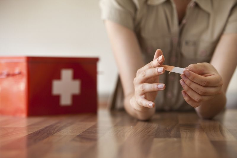 Frau wickelt sich Pflaster um den Finger