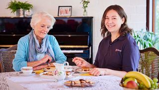 Eine junge und eine ältere Frau sitzen am Tisch und essen Kuchen.