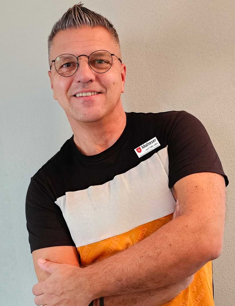 Porträt eines lächelnden Mannes mit Brille. 