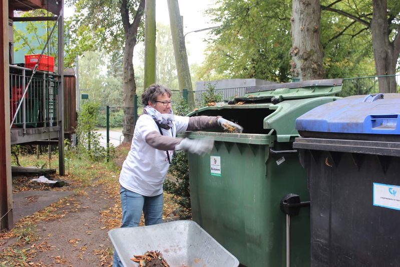 Doris schmeißt Laub in den Müll