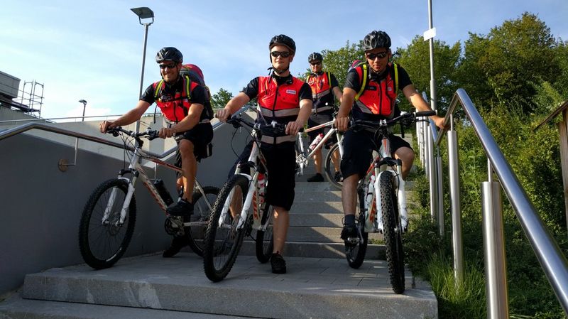 Vier Fahrradfahrer in roten Westen auf einer Betontreppe.