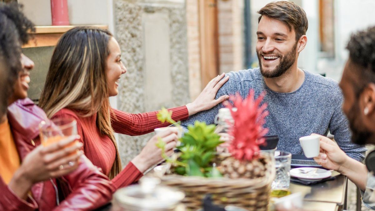 Junge Menschen lachen und essen an einem Tisch