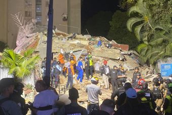 Zahlreiche Rettungs- und Einsatzkräfte stehen nachts auf den Trümmern eines eingestürzten Gebäudes in Caracas. (Foto: Yelitze Colmenares)