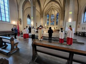 Messdiener und Pfarrer beim Gebet im Altarraum