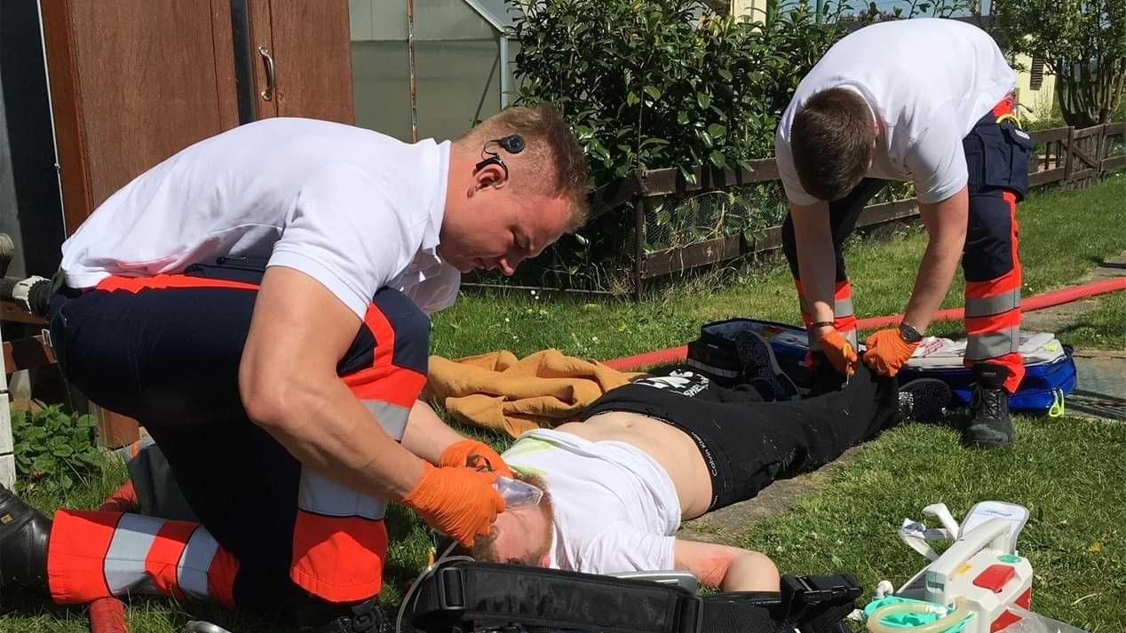 Zwei Sanitäter der Malteser versorgen einen am Boden liegenden Mann. 