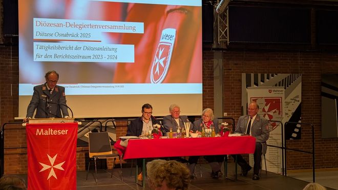 Der Diözesanvorstand sitzt auf dem Podium, während Dr. van Lengerich den Bericht vorträgt