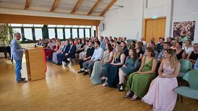 Ein Mann spricht an einem Rednerpult zu vielen Menschen.