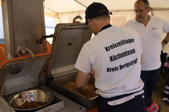 Ein Koch vom Küchenteam bereitet veganes Gyros zu. Ein anderer Malteser sieht dabei zu (Foto: Malteser Viernheim)