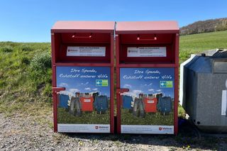 Zwei Altkleidercontainer der Malteser. Im Hintergrund blauer Himmel.