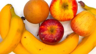 Bananen, Äpfel und Orangen auf einer weißen Fläche