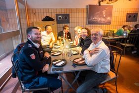 Mehrere Personen sitzen an einem gedeckten Tisch und lächeln in die Kamera.