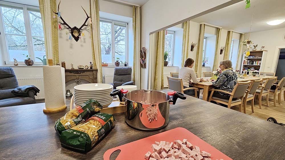 Blick aus der Gemeinschaftsküche auf den großen Gemeinschaftstisch