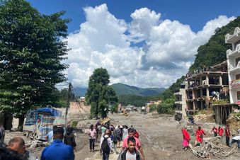 Menschen gehen durch eine von Schlamm und Geröll verwüstete Straße in Nepal. Foto: Prabin Shrestha/KOSHISH